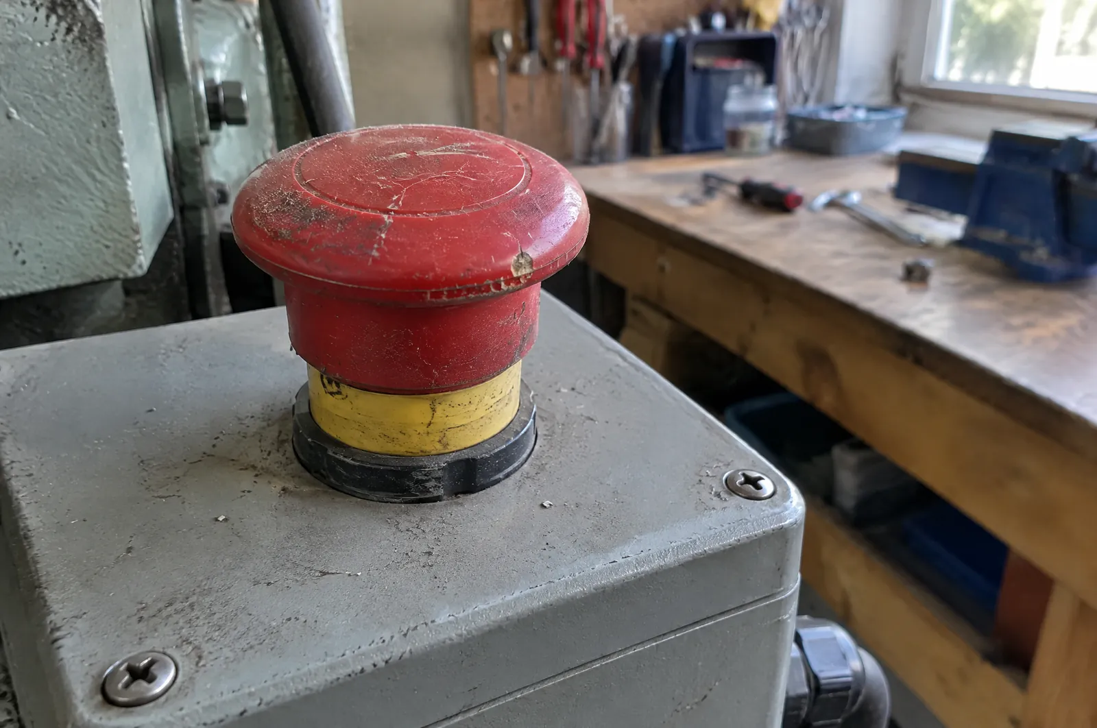 Rode noodstopknop op een bedieningskast in een werkplaats