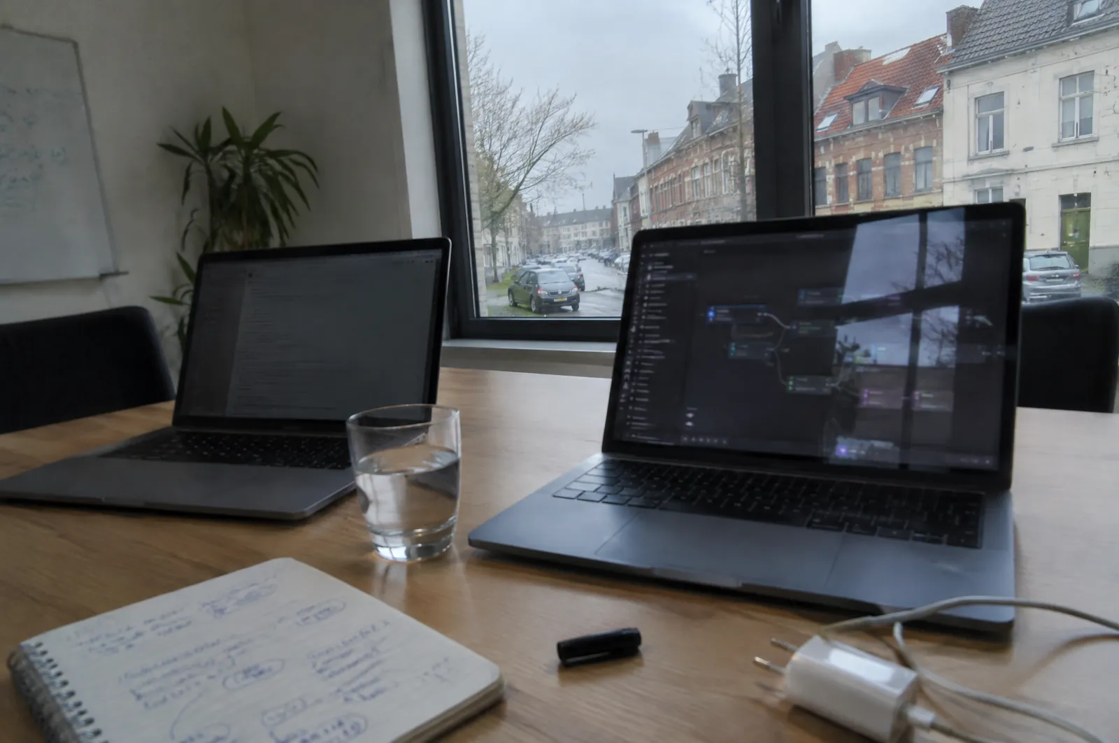 Twee laptops naast elkaar op een vergadertafel, elk met een ander schema van verbonden blokken op het scherm